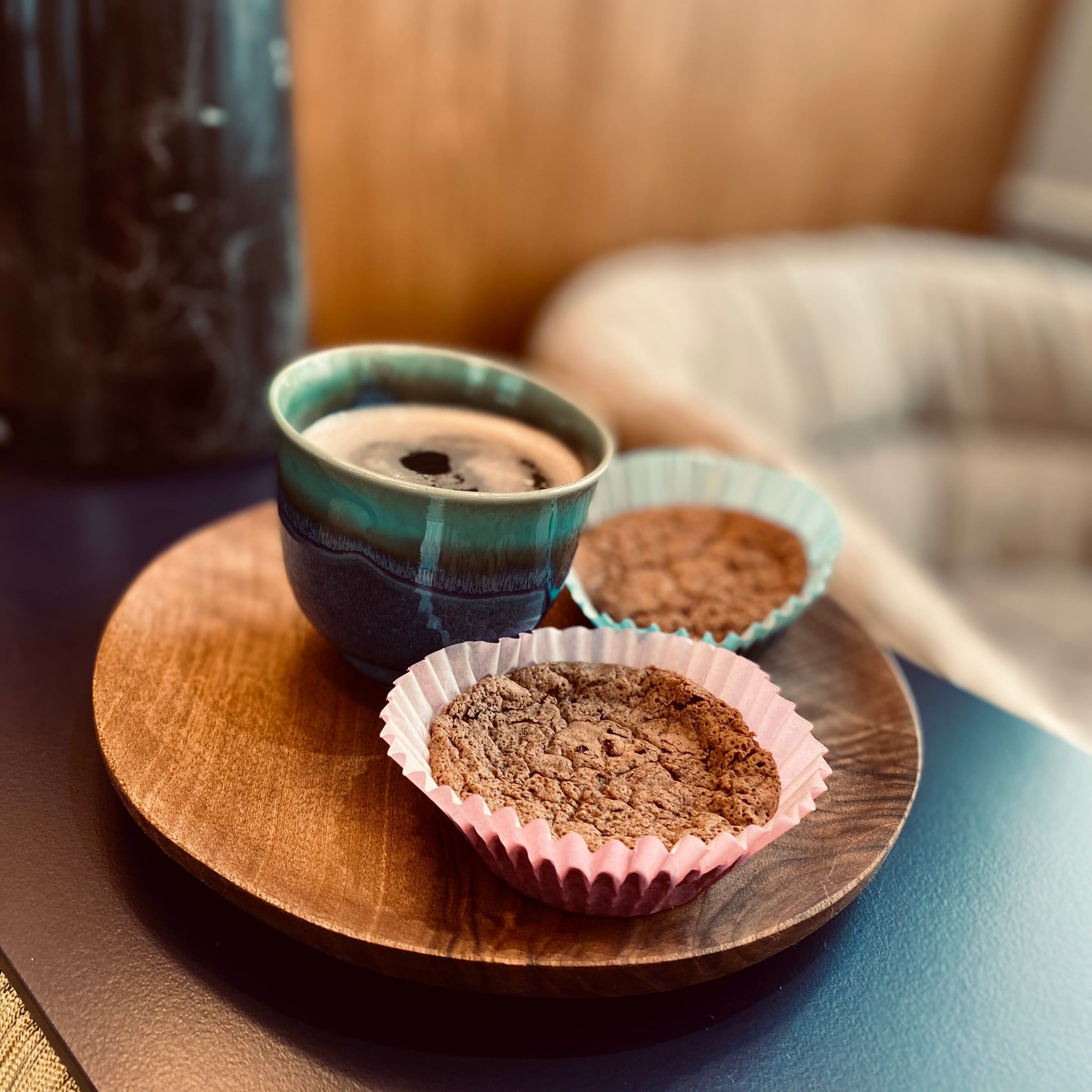 Café servi dans une tasse en céramique émaillée avec deux petits gâteaux sur un plateau en bois