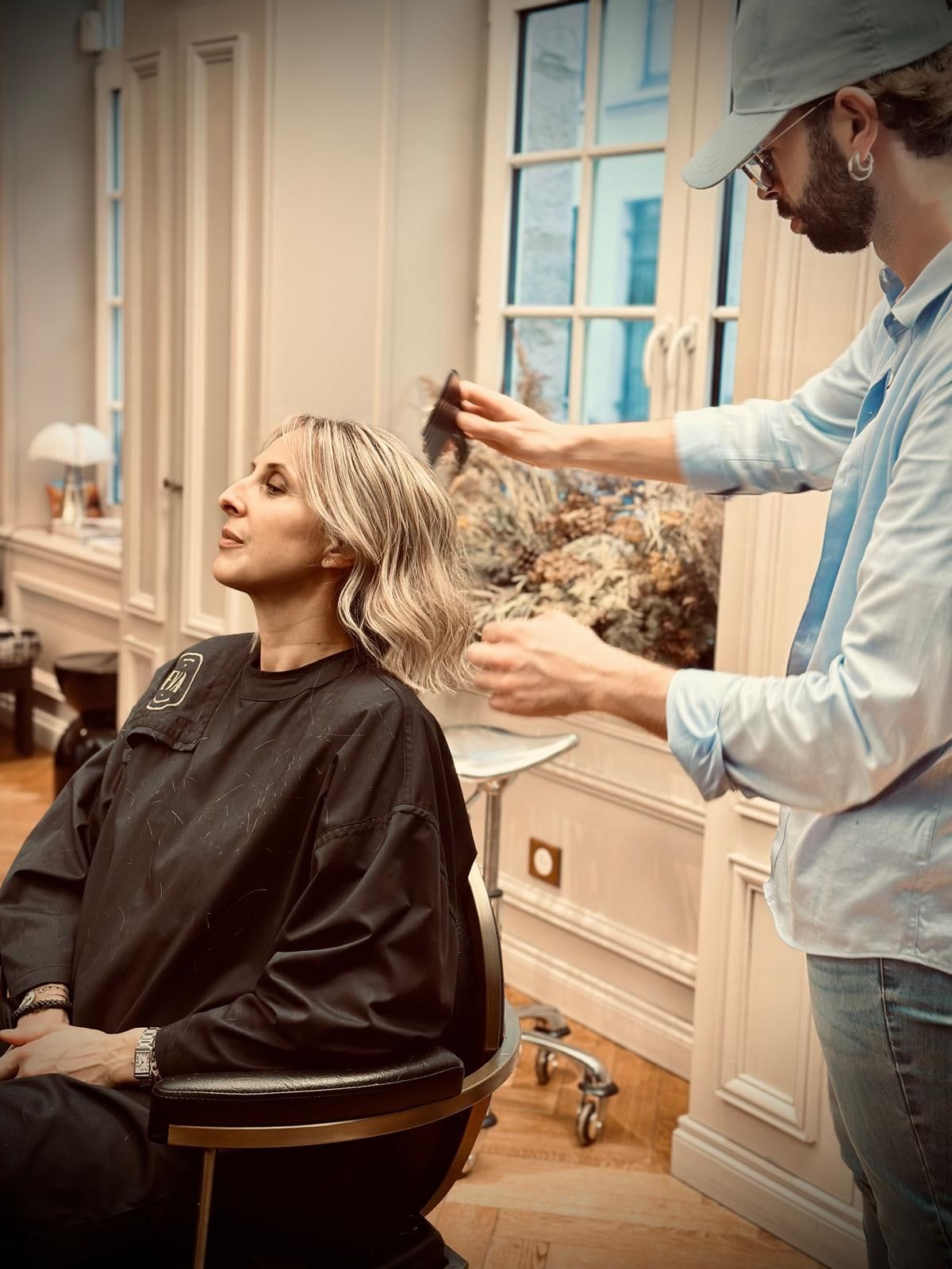 Coiffeur ajustant un carré flou blond sur une cliente assise au fauteuil, dans le salon Maison de Coiffure Eva du Vieux-Lille