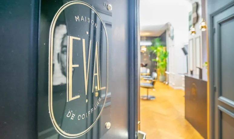 Porte d'entrée vitrée au logo doré Maison de Coiffure Eva, ouverte sur le salon, 20 rue des Tours à Lille