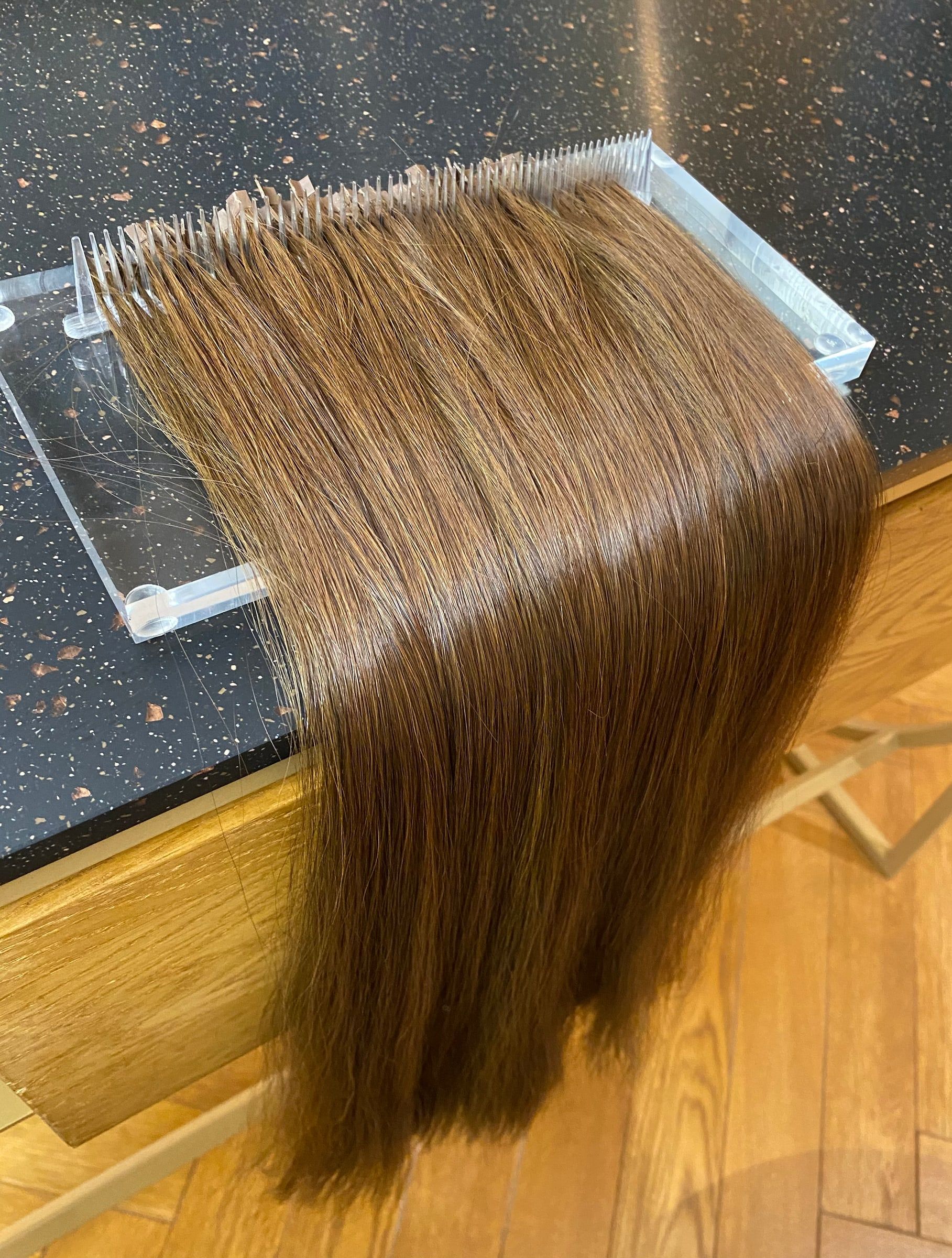 Mèches d'extensions Great Lengths châtain clair alignées sur un présentoir en plexiglas, au salon Maison de Coiffure Eva, Vieux-Lille