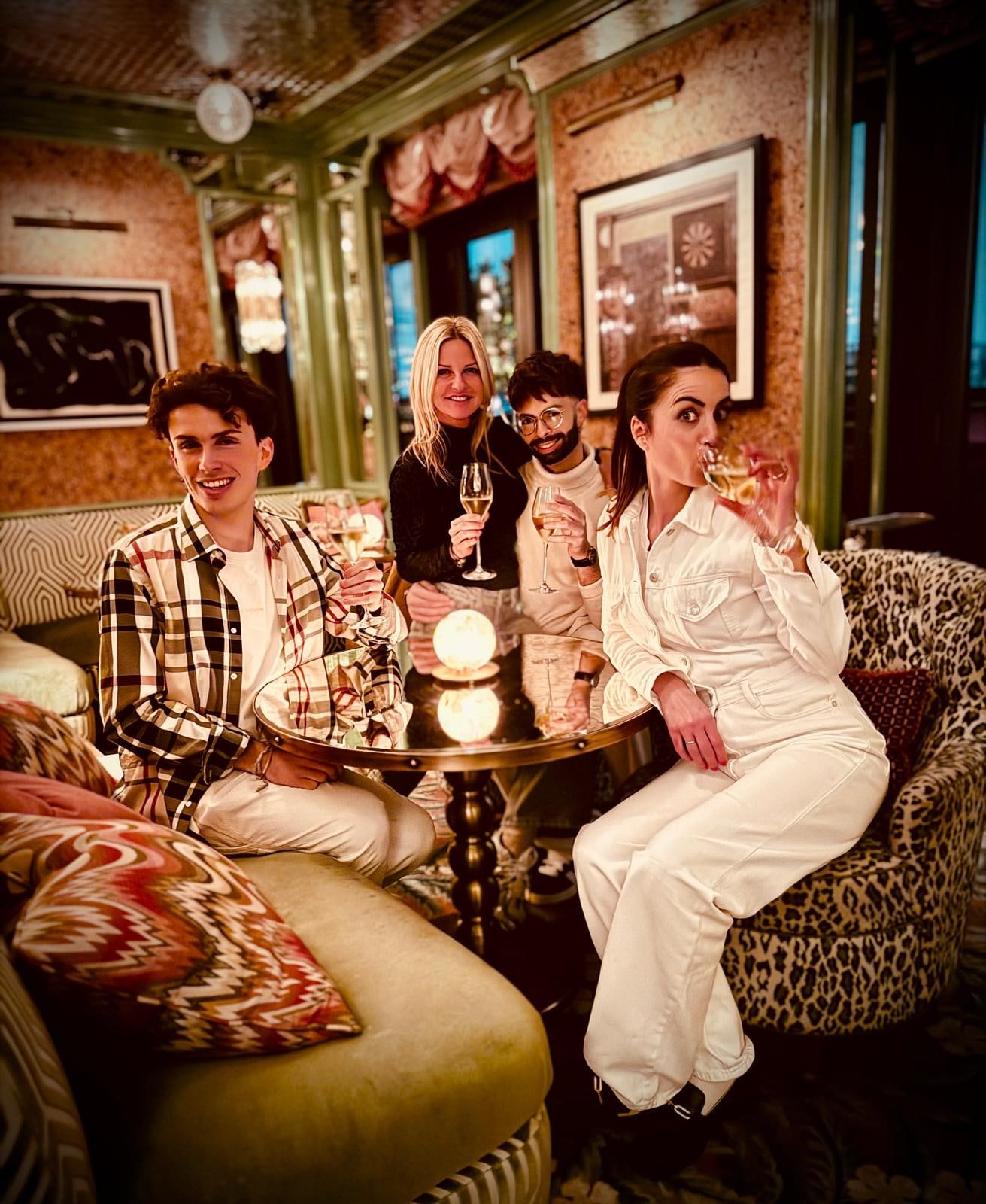 Soirée d'équipe : quatre coiffeurs de la Maison de Coiffure Eva trinquent dans un bar aux fauteuils léopard